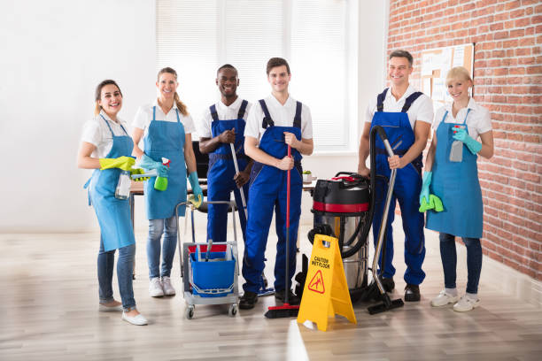 Home portrait of happy diverse janitors in the office with cleaning equipments